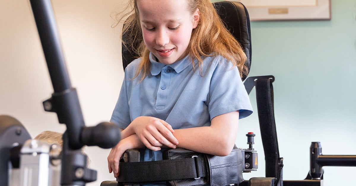 A girl standing in her Innowalk Pro, trying it for the first time and slightly smiling while looking down.