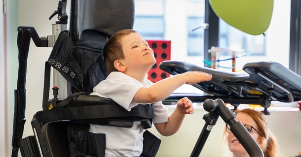 Young boy standing in his Innowalk Pro at school playing with a green ballon.
