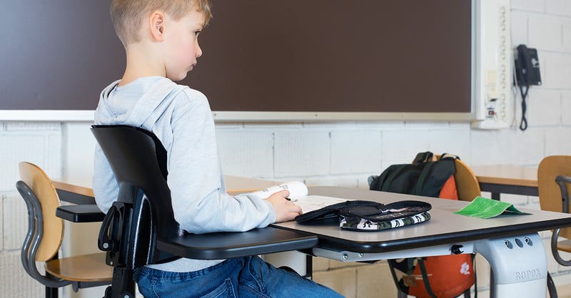 Ung pojke sitter i Jockey Lite i klassrummet.