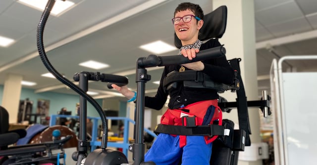 Eine lächelnde Person, die das Innowalk- und Gehgerät während des Rehabilitationstrainings benutzt.