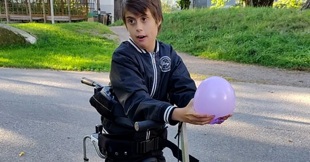 Ein junger Junge steht in seinem Xplore und spielt mit einem Ballon.