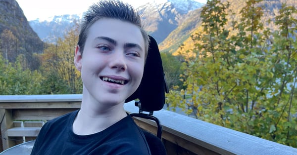 Närbild av ung kille som ler i rullstol.