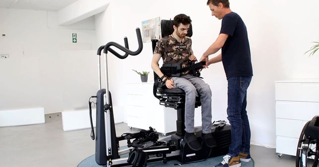 En ung man sitter i Innowalk och får en höftsele monterad av en sjukgymnast.