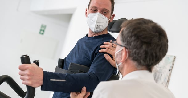 Man with face mask in Innowalk and their therapist 