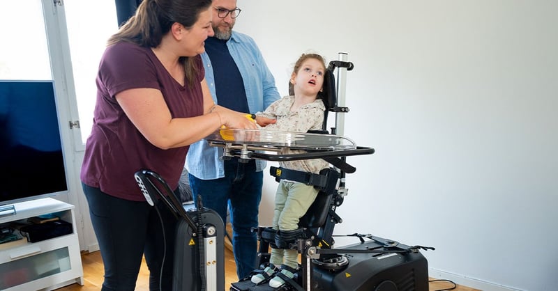 Ung flicka står i sin Innowalk medan mamma och pappa tittar på henne.