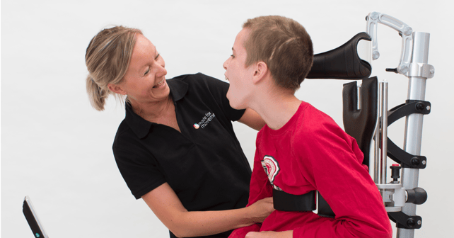 Woman helping a boy adapt the equipment. How to transfer the user in and out of the Innowalk.