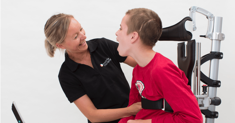 Woman helping a boy adapt the equipment. How to transfer the user in and out of the Innowalk.