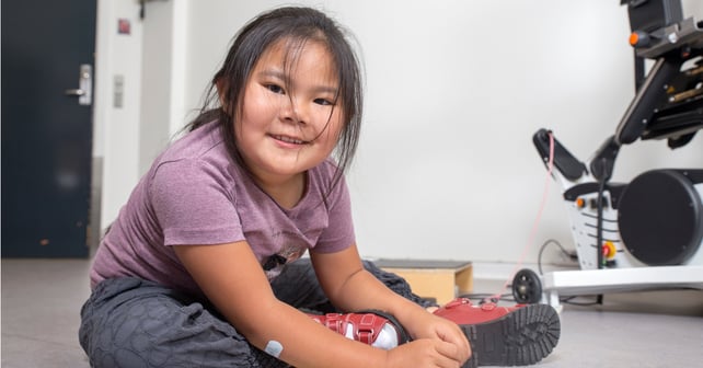 Girl with SMA sitting on the floor.