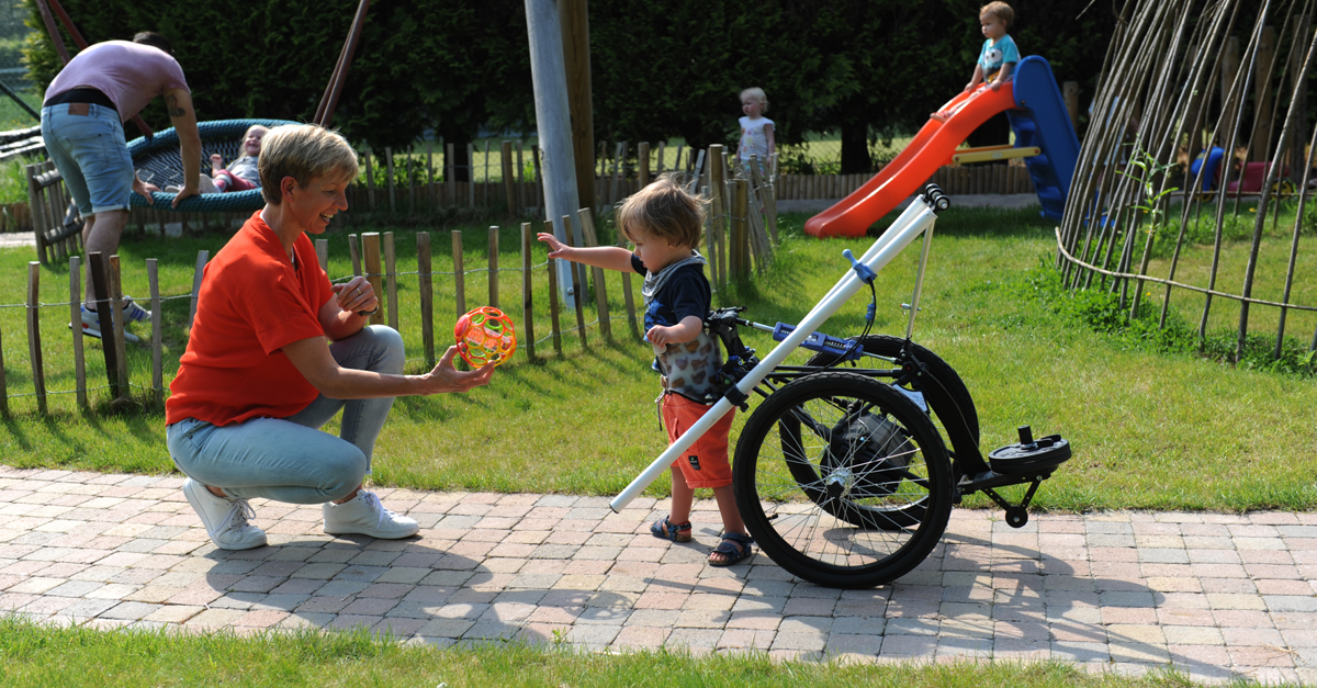 Ria Cuppers playing in the park with a small boy in his Hibbot assitive device