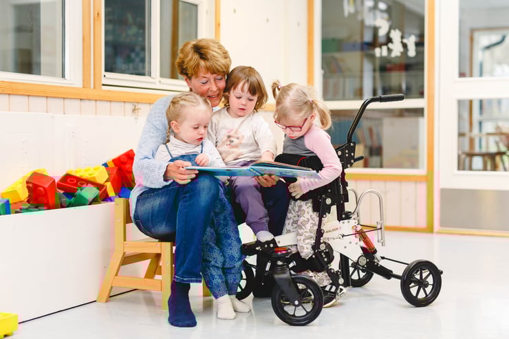 Jente står i NF-Walker og leser en bok med vennene sine