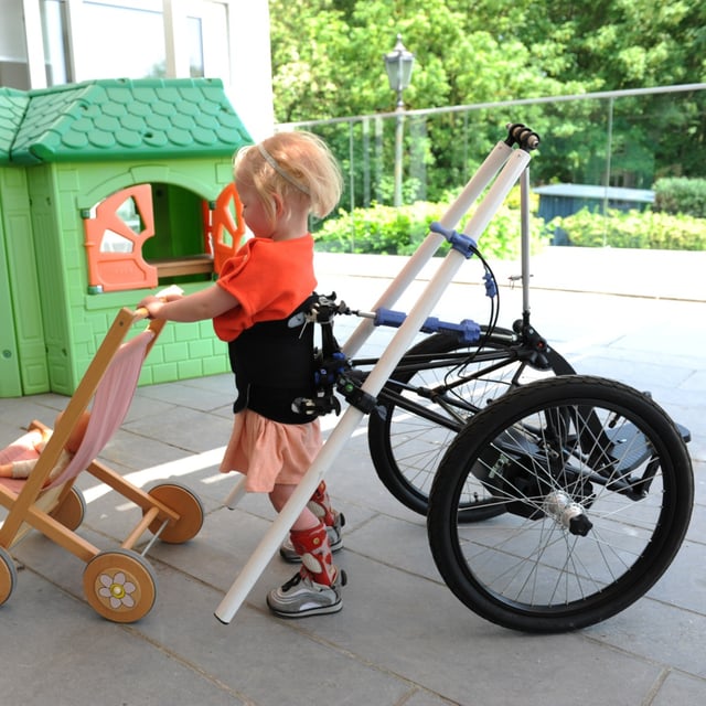 Kind im Hibbot laufend, mit einem Spielzeugbuggy vor sich