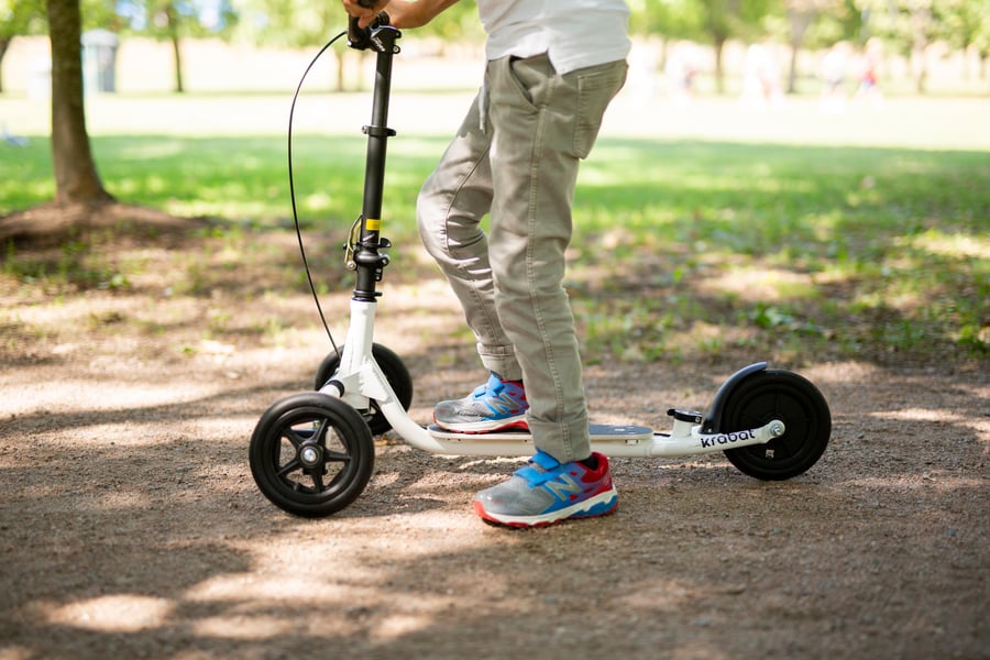 Pojke står med en fot på sin sparkcykel Krabat Runner.