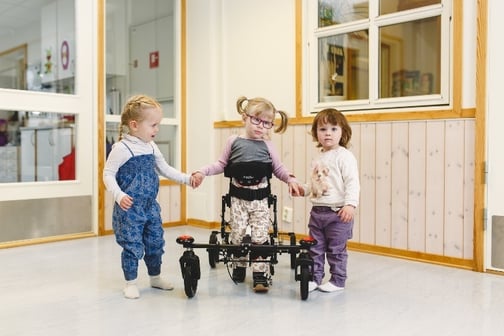 Jente går i sin NF-Walker og holder hendene til sine venninner