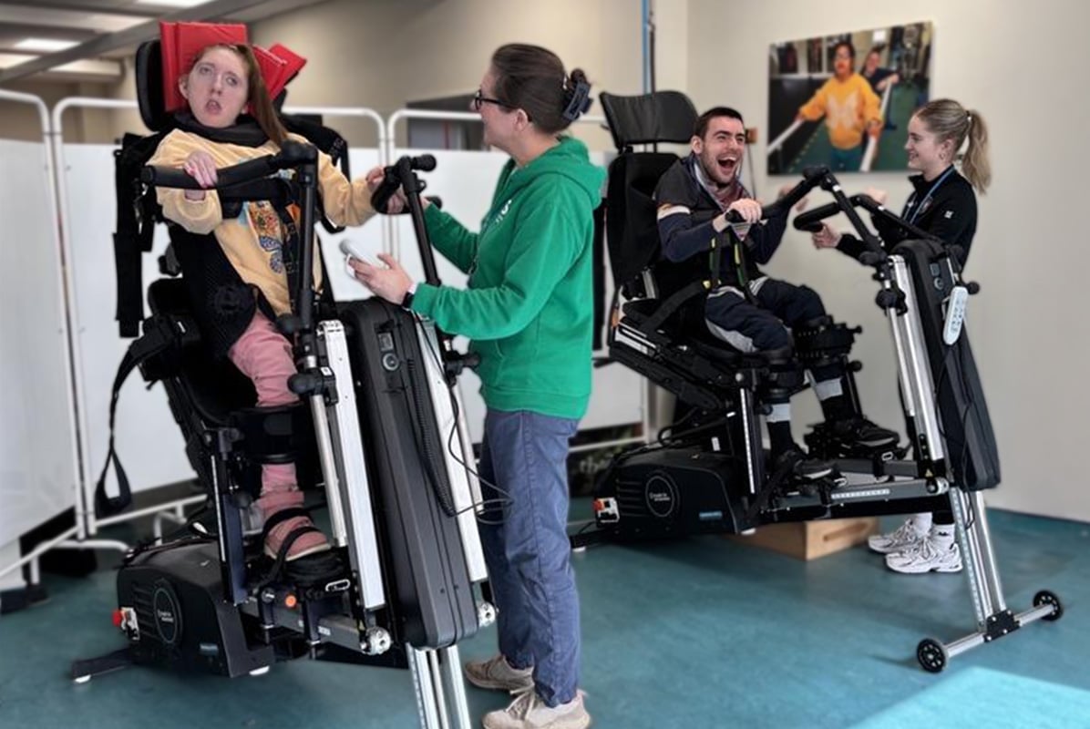 Two people using Innowalk Pro devices during a supported therapy session with therapists assisting nearby.