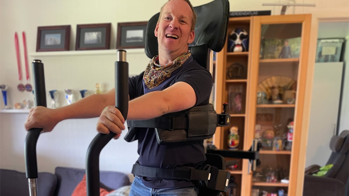 Mann steht aufrecht im Innowalk drinnen und lächelt.