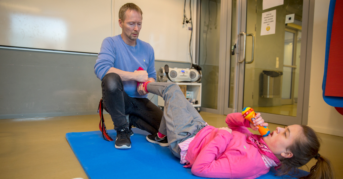 Girl with disability doing stretching exercises with teacher. 