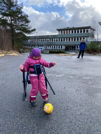 Ung flicka spelar fotboll med hjälp och stöd av Hibbot