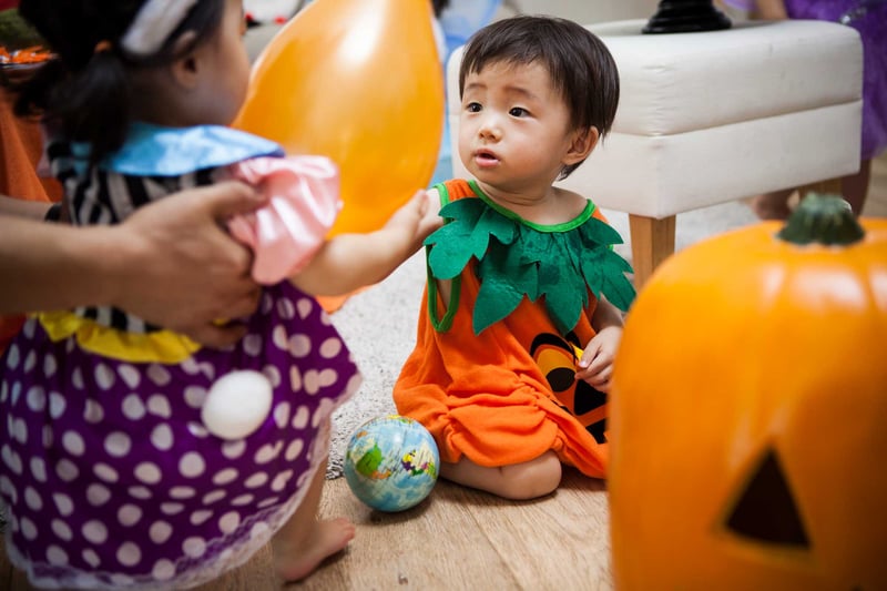 Two young children are disguising and playing with balloons