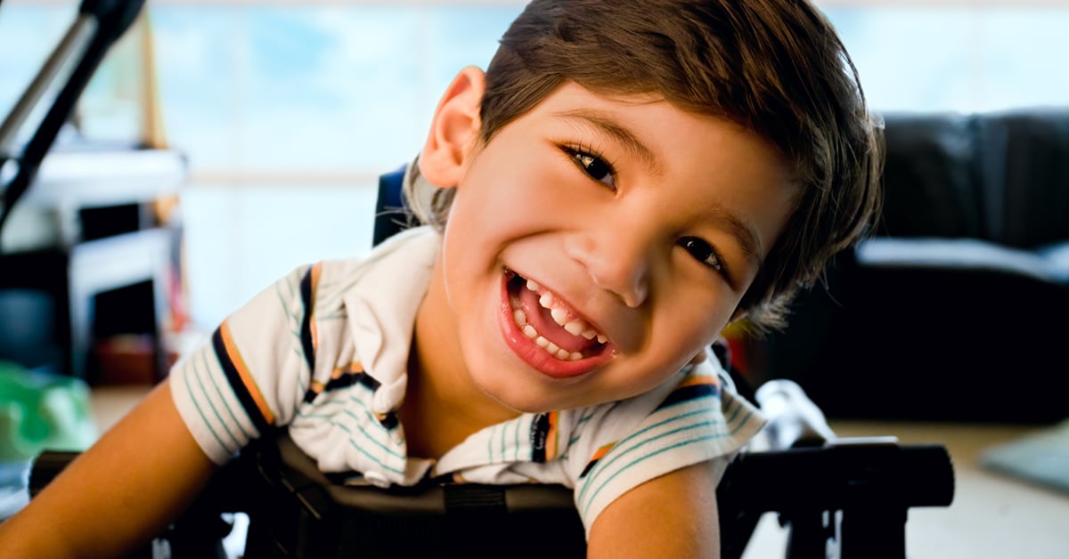 Disabled little boy standing in walker smiling